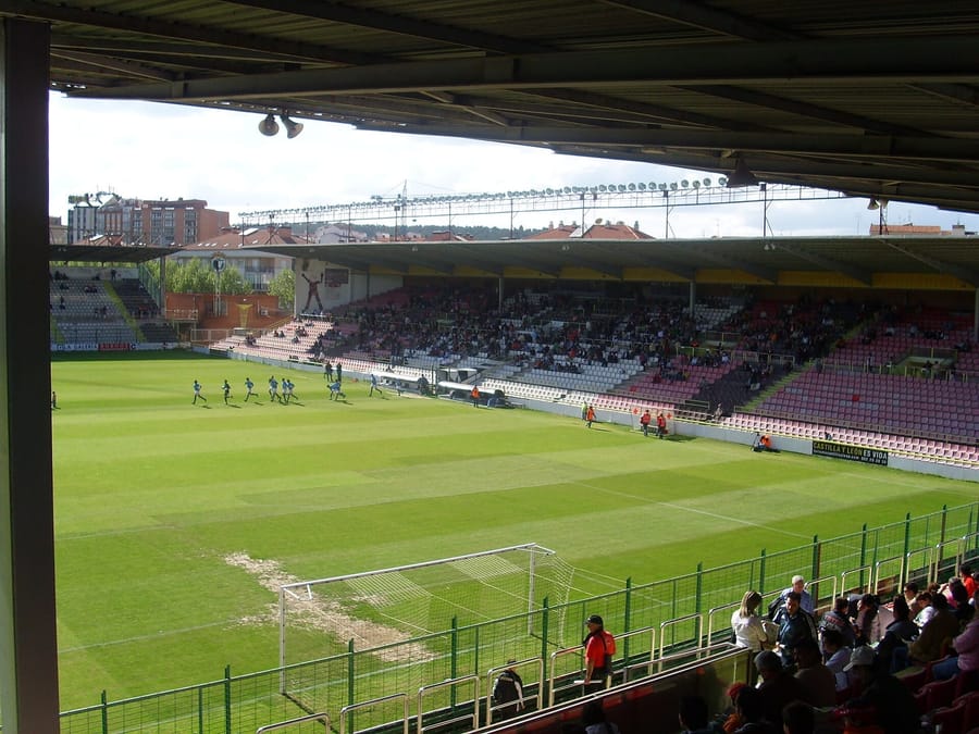 Vista des de la graderia del camp i les graderies d'un estadi del Burgos CF, amb jugadors escalfant a la gespa